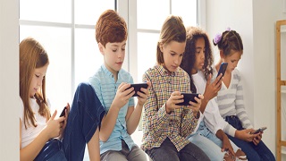 A group of children all on their phones and devices.