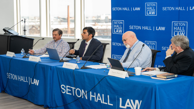 Four people seated at a long table talking