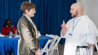 A woman talking to a bold priest