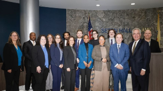 People stand together in front of flags