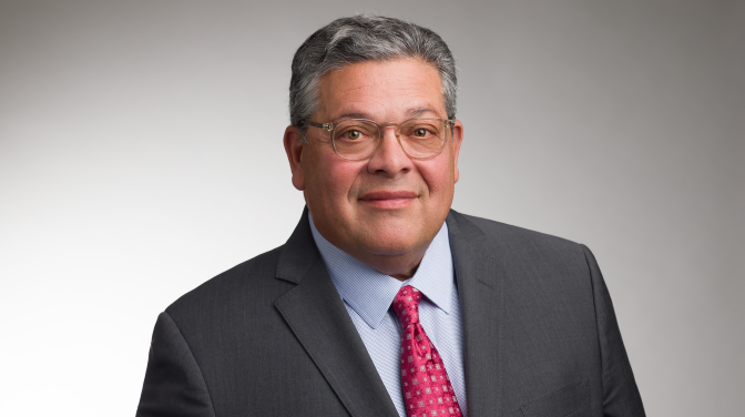bespectacled man wearing a red tie and suit