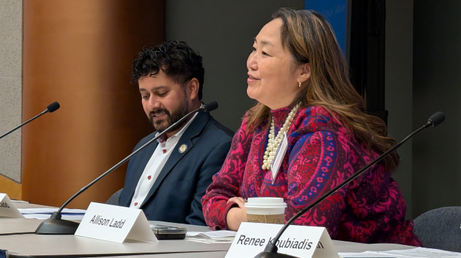 Two people seated by mics