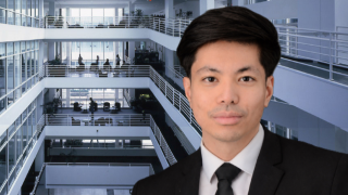 Asian man in front of building interior railings