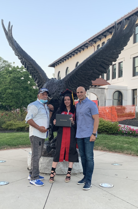 Three people standing in front of an Eagle statue
