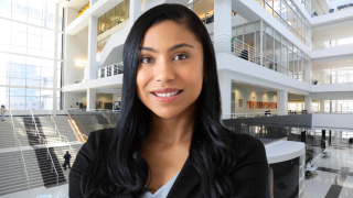 Latina woman smiling inside a building with white beams
