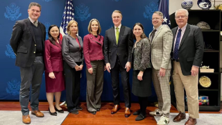Group of white people posing in front of a flag