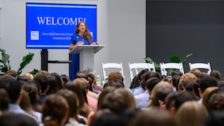 white woman talking to students from a stage