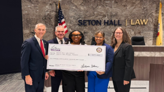A black woman holding a check in the middle of a group