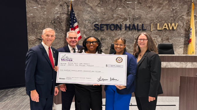 A black woman in the center holding a check.