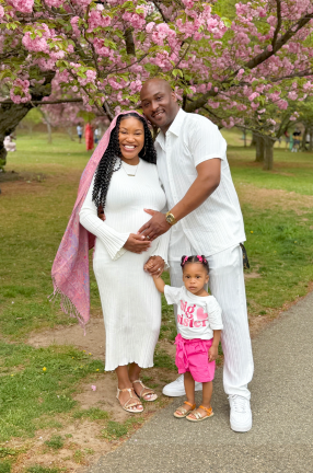 three black people standing together under a tree.