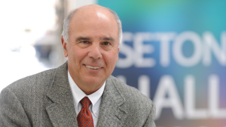 Bold white man smiling in front of a sign