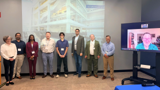 group of people posing next to a screen