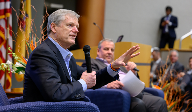 A seated man talking with a microphone with a blurred background