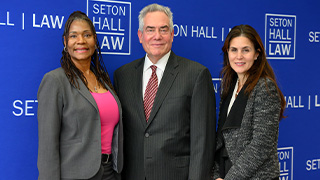Three people standing in front of a step & repeat