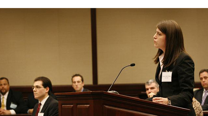 white woman in suite speaking at podium