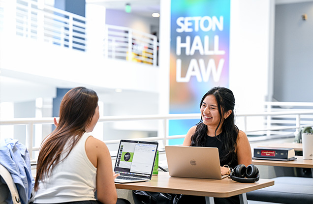 Two students sitting together on their laptops