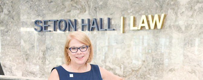 Dean Kathleen M. Boozang with Seton Hall Law behind in Moot Court Room.