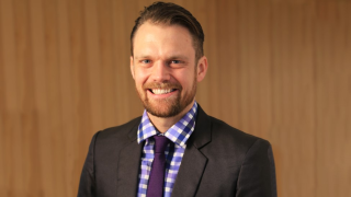 White man with beard smiling wearing suit and tie