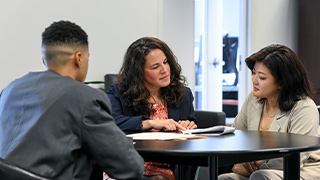 A photo fo three people working together around a conference table.